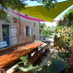 Les tables de jardin sous les voiles d'ombrage du gite de groupe