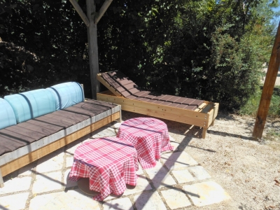 Profitez du salon de jardin du gite de groupe : une banquette et un bain de soleil sous la pergola.